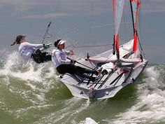 two people riding on top of a sailboat in the ocean