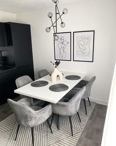 a dining room table and chairs with pictures on the wall behind it in black and white