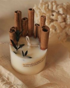 some cinnamon sticks are sticking out of a bottle that is filled with white liquid and black leaves