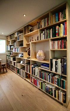 a bookshelf filled with lots of books next to a table and chair in a room