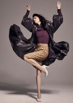 a woman in a purple top and black jacket is dancing with her legs spread out