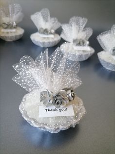 several small white baskets with flowers and thank you tags on them sitting on a table