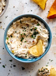 a blue bowl filled with potato chips and dip