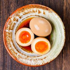 three hard boiled eggs in a bowl on a wooden table