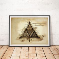 a framed print of a triangle with three different symbols in it on a wooden floor