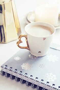 a cup of coffee sitting on top of a table next to a notebook and pen