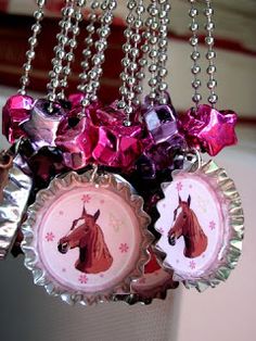 the bottle caps are decorated with pink and purple ribbons hanging from silver chains on a window sill