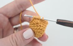 someone is crocheting an object with yarn on the tip of a knitting needle