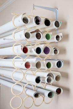 the wall is filled with different colors of paint and tubes hanging from it's hooks