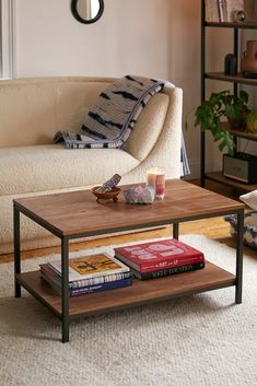 a living room with a couch, coffee table and books on the shelf in front of it