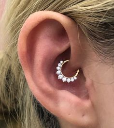 a woman's ear is shown with a small diamond hoop in the shape of a crescent