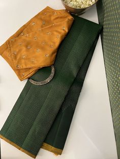 A gorgeous green monotoned pure handwoven kanchipuram silk saree with a beautiful mustard selvedge and blouse may seem simple at first glance but the magic is all packed into the pure zari work thats so intricately and thoughtfully done on it. Delicate pure zari threads gradually ascend along the border, reaching their peak at the pallu. In an unexpected twist, the pallu is with traditional muthu lines , adding a unique touch to its elegance. Mysore Silk Saree Styling, Modest Blouse, Simple Saree Designs, New Saree Designs, Silk Saree Kanchipuram, Cotton Saree Designs