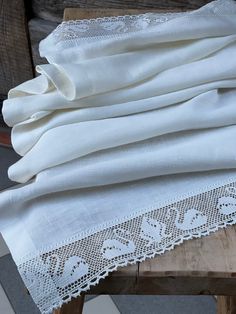 an image of white linens on a wooden table with lace around the edges and bottom