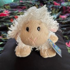 a stuffed animal with white hair sitting on top of a black pillow covered in flowers