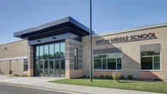 the front entrance of a school building with windows and grass on the side of the street