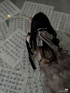 a woman laying on top of sheets of paper with writing all over her body and head