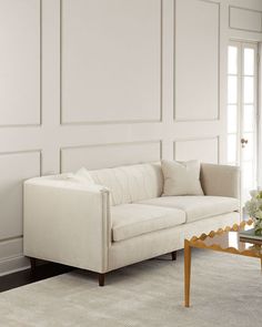 a living room with white walls and furniture in the corner, along with a glass coffee table