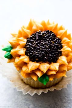 there is a cupcake decorated like a sunflower with chocolate chips on the top