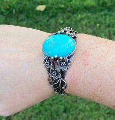 Gorgeous, large cuff bracelet in Sterling silver covered with flowers and botanical details holding large, oval blue stone with gold veining.  The cuff is marked 925.   42 grams with stone 2.25 inches across (inside measurement) 6.5 inches internal diameter including gap Gap is 1 inch but cuff does have some flexibility Blue Oval Gemstone Cuff Bracelet, Unique Blue Oval Cuff Bracelet, Blue Oval Vintage Cuff Bracelet, Large Cuff Bracelet, Beach Jewelry Boho, Sterling Silver Cuff, Beach Jewelry, Silver Cuff, Blue Stone