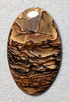 an oval shaped wooden object with brown and black swirls on the top, sitting on a gray surface