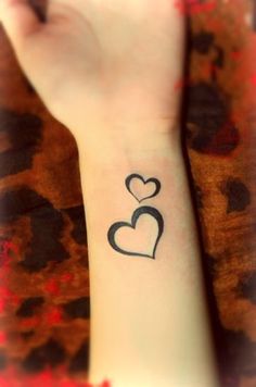 a small wrist tattoo with two hearts on it