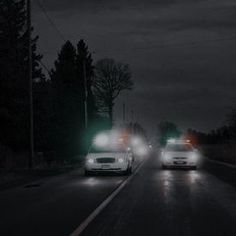 two cars driving down the road at night