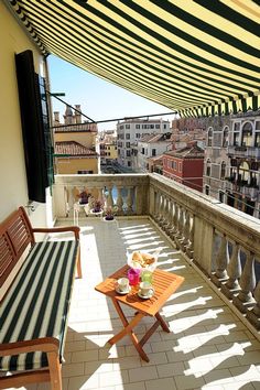 a balcony with striped awnings and wooden furniture