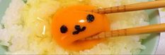 two chopsticks sticking out of rice with an orange smiley face on it,