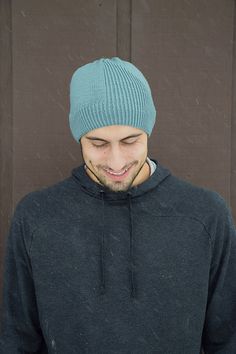 a man wearing a blue hat standing in front of a brown door with his eyes closed