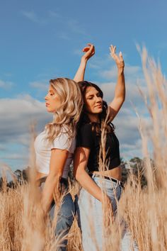 two women standing in tall grass with their arms up