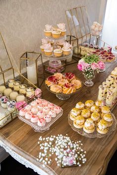 a wooden table topped with lots of cupcakes and pastries on top of it