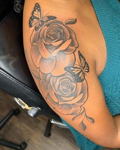 a woman's arm with a rose and butterfly tattoo on the side of her shoulder