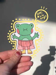 a person holding up a sticker with a frog on it