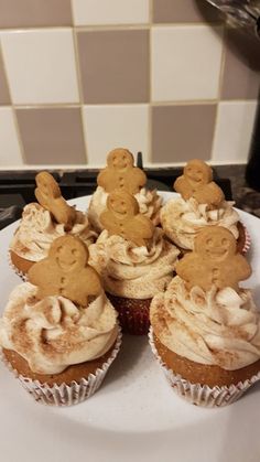 cupcakes with icing and ginger faces are on a plate