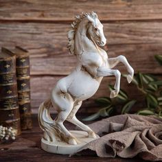 a statue of a white horse standing on its hind legs in front of some books