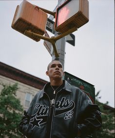 a man standing under a street light with luggage strapped to the back of his jacket