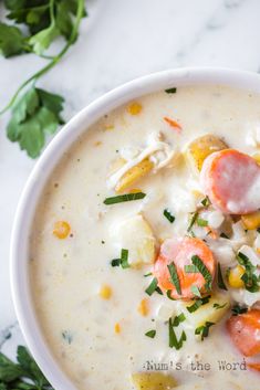 a white bowl filled with soup on top of a marble counter next to green leaves