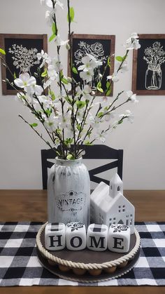 a vase with white flowers in it sitting on a table next to some small houses