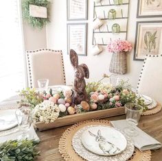 a dining room table set for easter with bunny figurines and flowers in the center