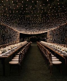 a long table is set up with white flowers and lite - up lights on the ceiling