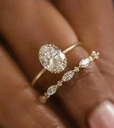 a woman's hand holding a ring with two pear shaped diamonds on top of it