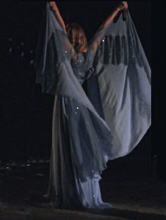 a woman in a blue dress with her arms outstretched