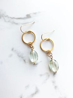 Modern, luxe earrings featuring beautiful faceted green amethyst gemstones. These earrings are great for work or everyday wear. Lovely pale green is a hit for spring. + Green Amethyst. 14K Gold Fill Ear Wire. 14K Gold Plate Circle. + Length: 2 inches. + Earrings are ready to ship. + Your jewelry will come in a jewelry box, tied with a ribbon. ➤➤ Have a question about this product, reach out to me here ➙ https://www.etsy.com/conversations/new?with_id=9057464&referring_id=5772224&referring_type=sh Green Amethyst Dangle Earrings As Gift, Green Amethyst Gemstone Dangle Earrings, Everyday Briolette Gemstone Earrings, Green Amethyst Dangle Earrings For Gift, Dangle Earrings With Green Amethyst Gemstone, Modern Earrings With May Birthstone Gemstone, Elegant Faceted Green Amethyst Earrings, Green Amethyst Gemstone Earrings, Faceted Green Amethyst Earrings Gift