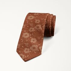 a brown tie with flowers on it is laying on the ground in front of a white background