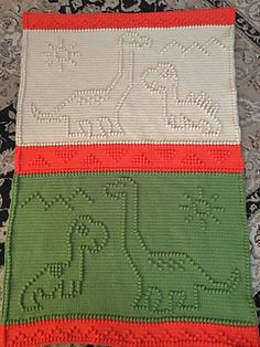 three crocheted placemats with dinosaurs on them, one is green and the other is red