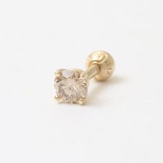 a pair of yellow gold studs with a white diamond in the center on a white background