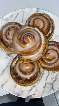 several cinnamon rolls on a white marble plate