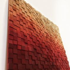 a large wooden wall hanging on the side of a white wall next to a vase