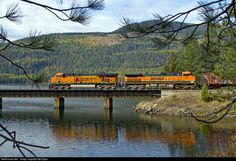 an orange train traveling across a bridge over water