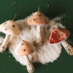 three different colored mushrooms sitting on top of some white snow covered ground with gold and silver decorations